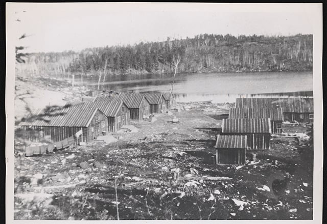 Log structures on a deforested piece of land next to a river.